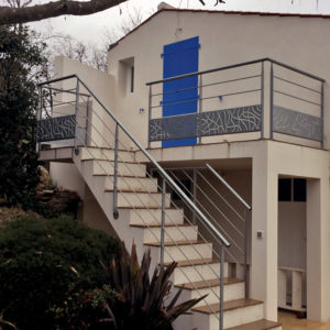 Habillage d'un escalier droit extérieur en béton (marches carrelées) d'accès à une terrasse d'un particulier. Rampe : poteaux métalliques plats tournés, main courante cylindrique métal et lisses droites métalliques. Garde corps : main courante cylindrique, poteaux métalliques plats tournés, lisses droites métalliques et soubassement tôle style "Algues".