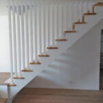 Escalier une crémaillère de jour en bois avec crémaillères teintées blanc et marches vernis mat