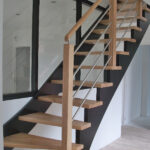 Escalier une crémaillère de jour en bois avec crémaillères teintées noir et marches vernis mat