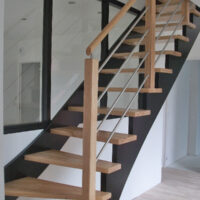 Escalier une crémaillère de jour en bois avec crémaillères teintées noir et marches vernis mat