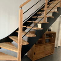 Escalier une crémaillère de jour en bois avec crémaillères teintées noir et marches vernis mat
